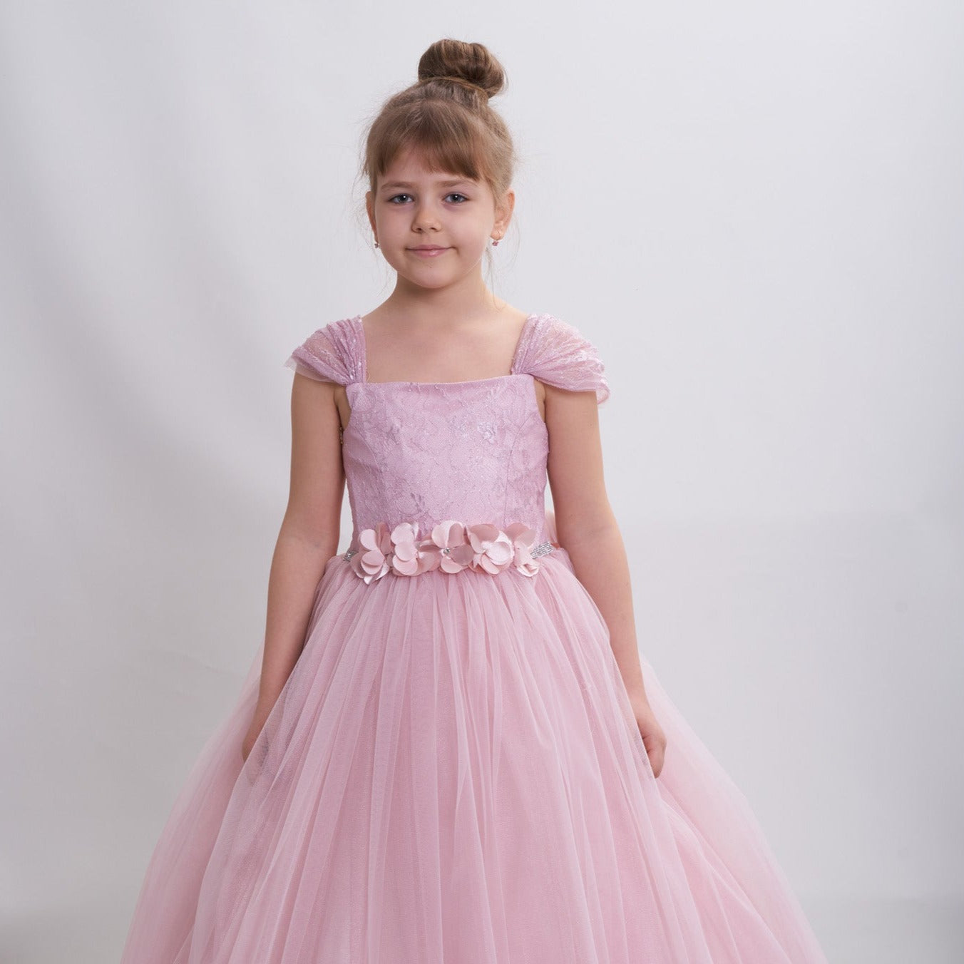 The Loveable Princess Girls Formal Dress features a pink tulle skirt, floral belt, and delicate cap sleeves.