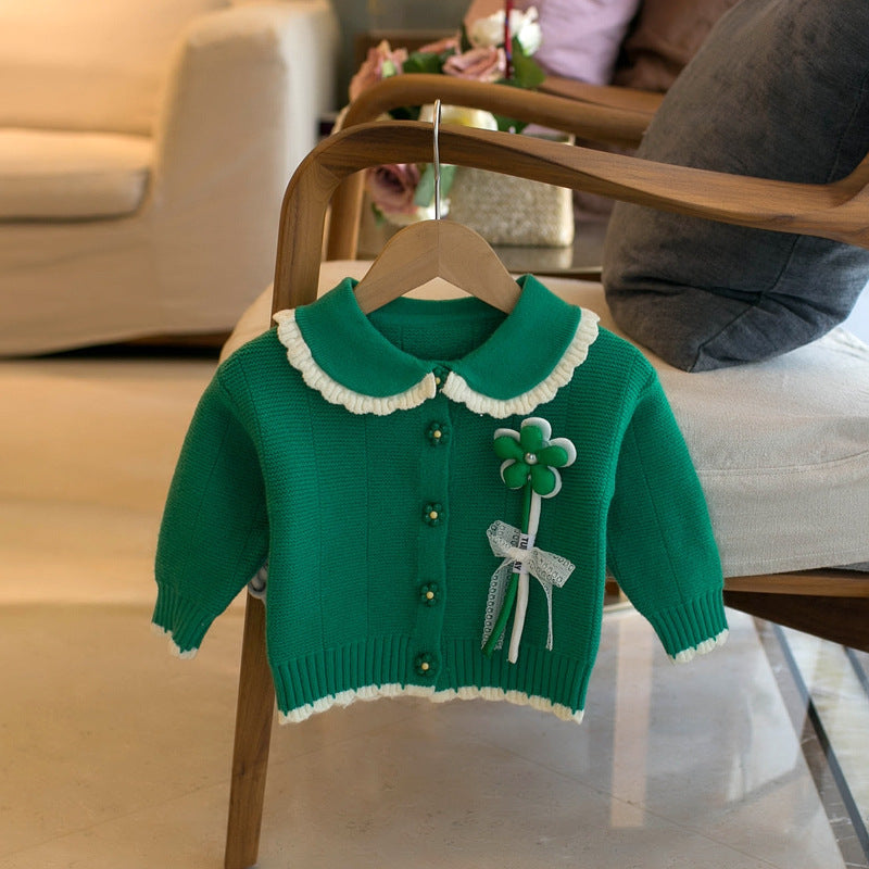 Green children's cardigan with a round collar, flower embellishment, and button closure. Perfect for girls.
