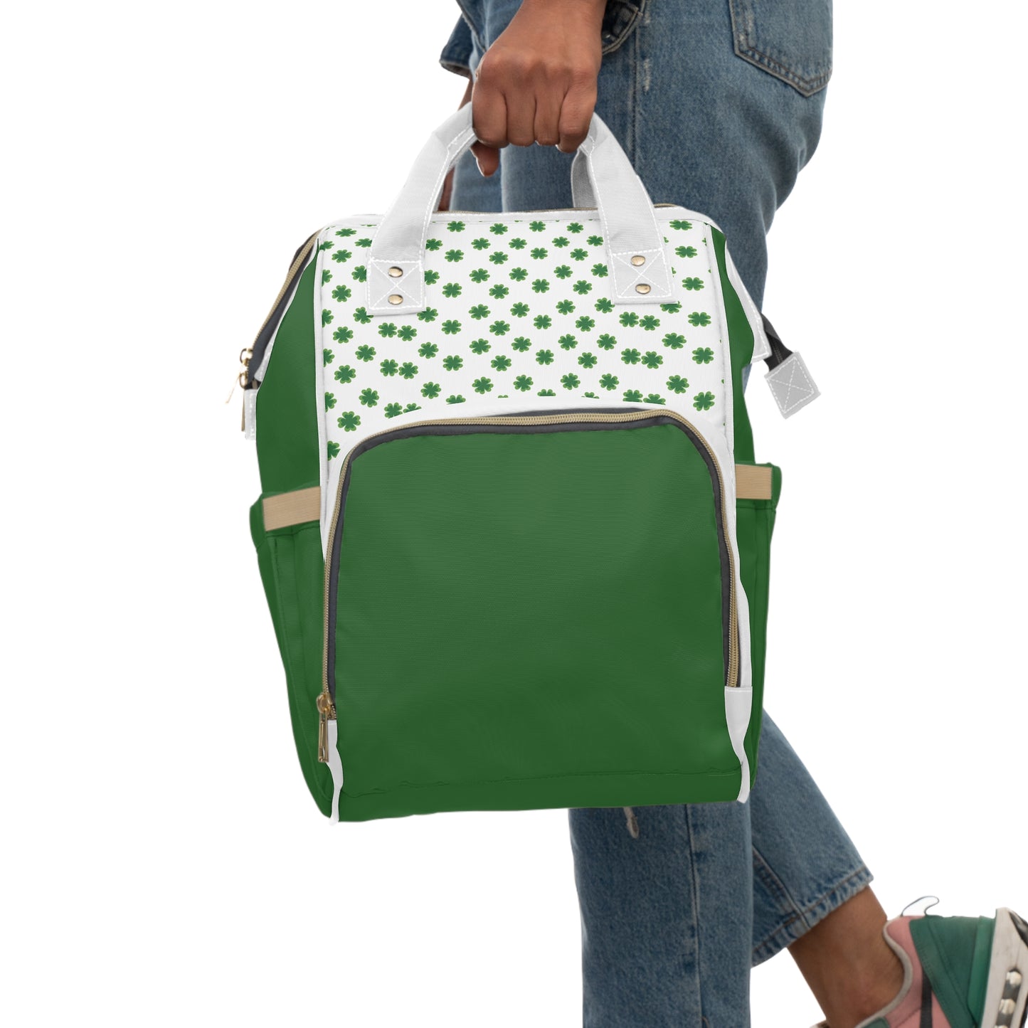 Clover Diaper Backpack featuring a shamrock print, green body, and white top, held by a person in casual attire.