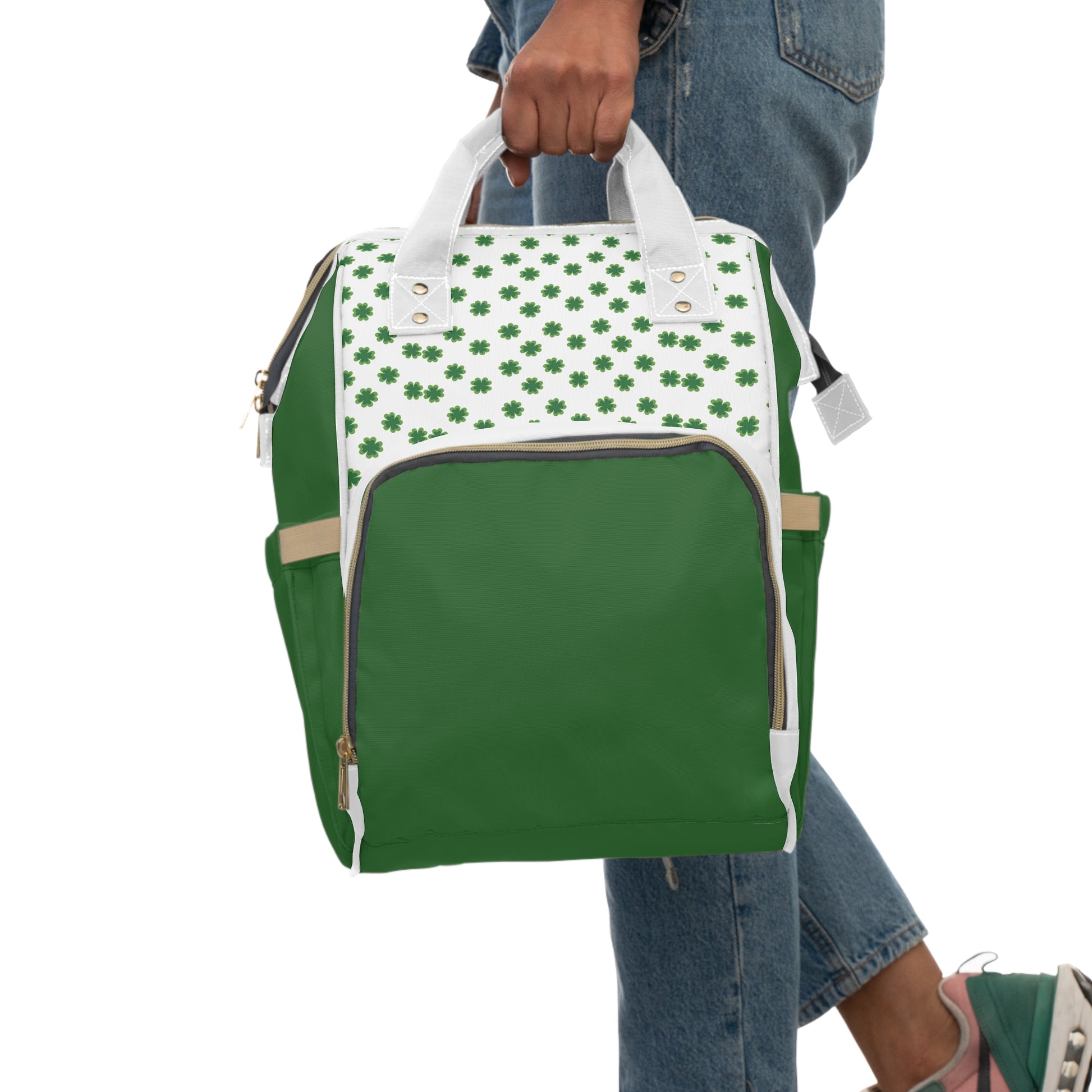 Clover Diaper Backpack featuring a shamrock print, green body, and white top, held by a person in casual attire.