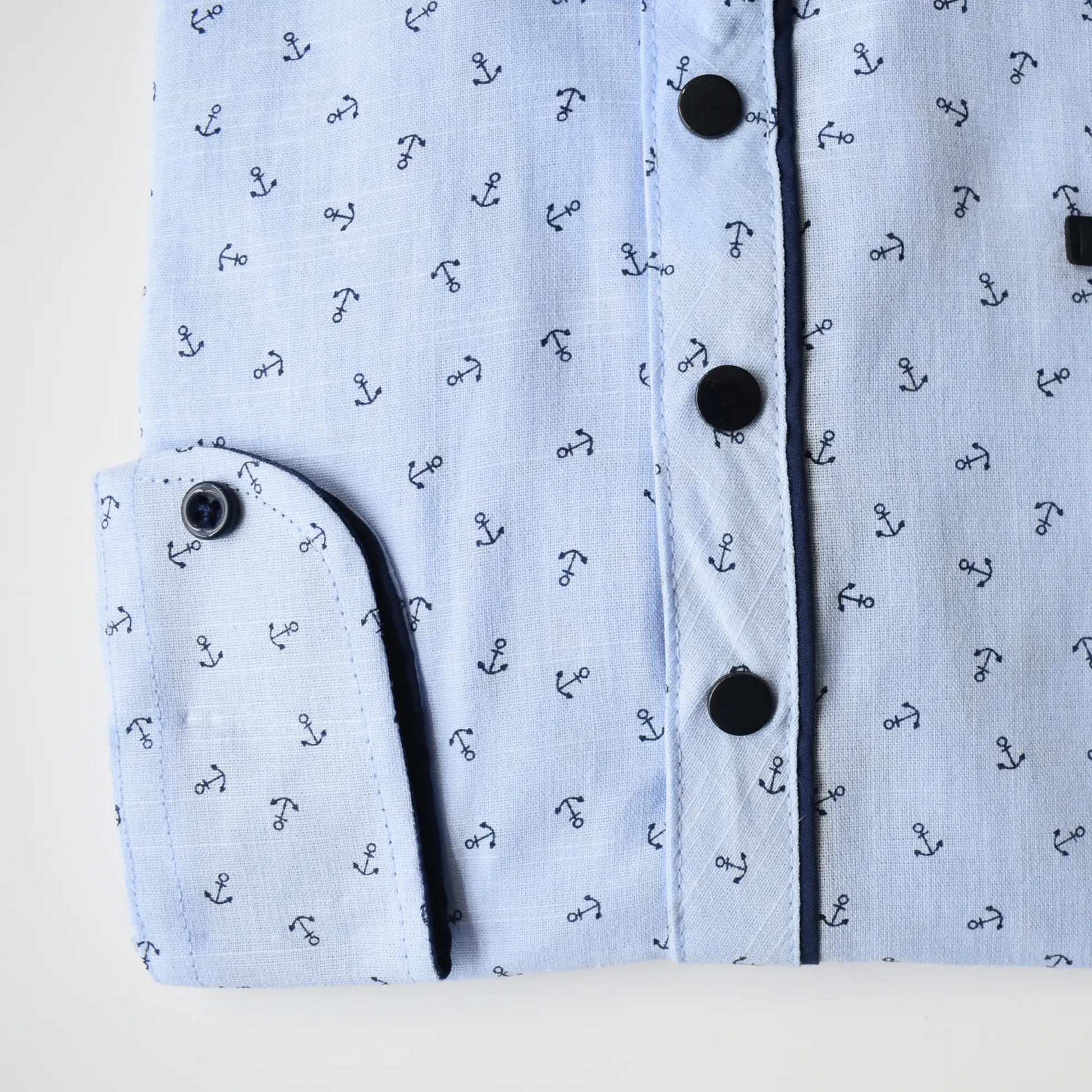 Light blue Anchor Boys Cotton Shirt featuring a nautical anchor pattern and black buttons. Folded sleeve detail visible.