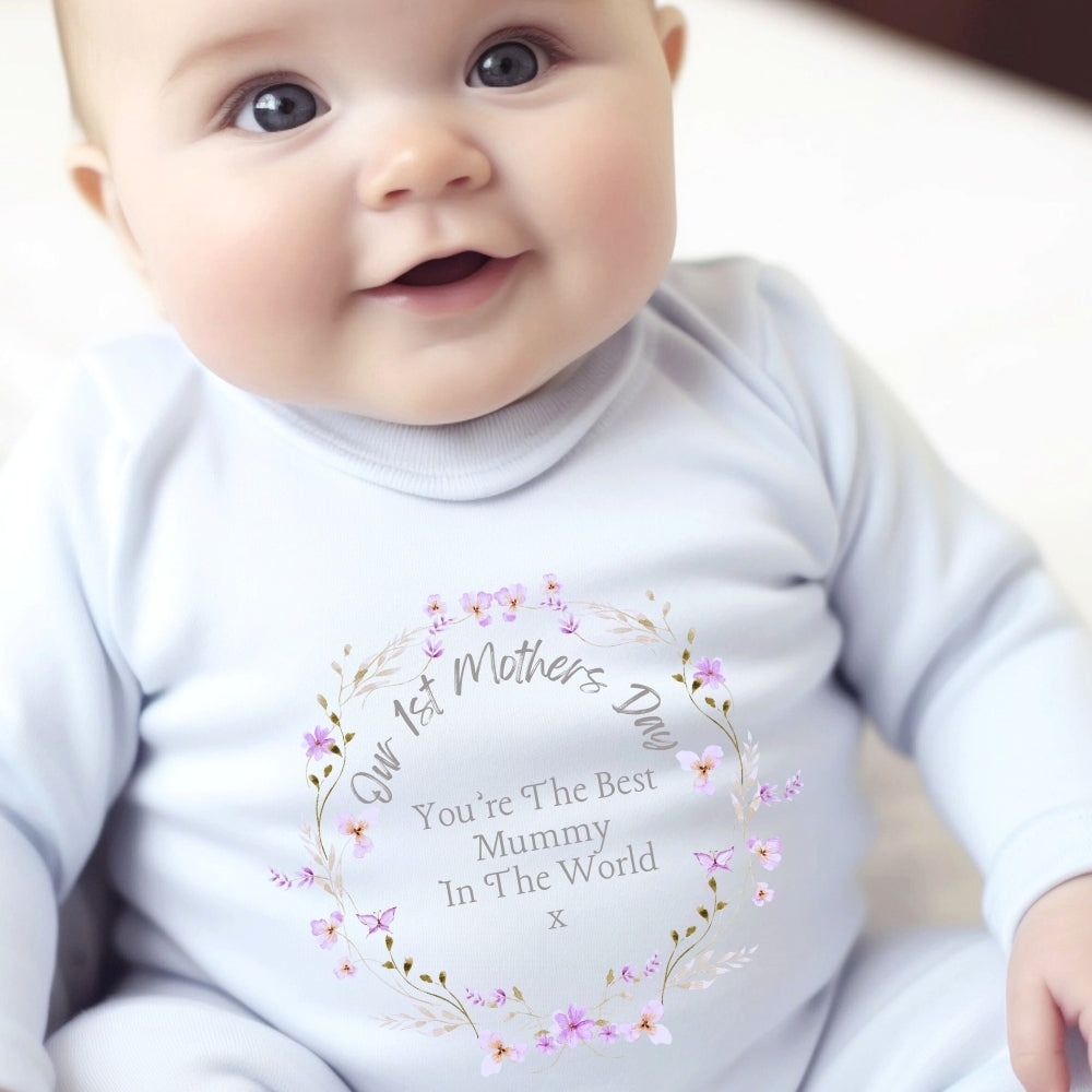 Baby wearing a light blue outfit with a floral design, featuring the text "Our 1st Mother's Day" and "You're The Best Mummy I