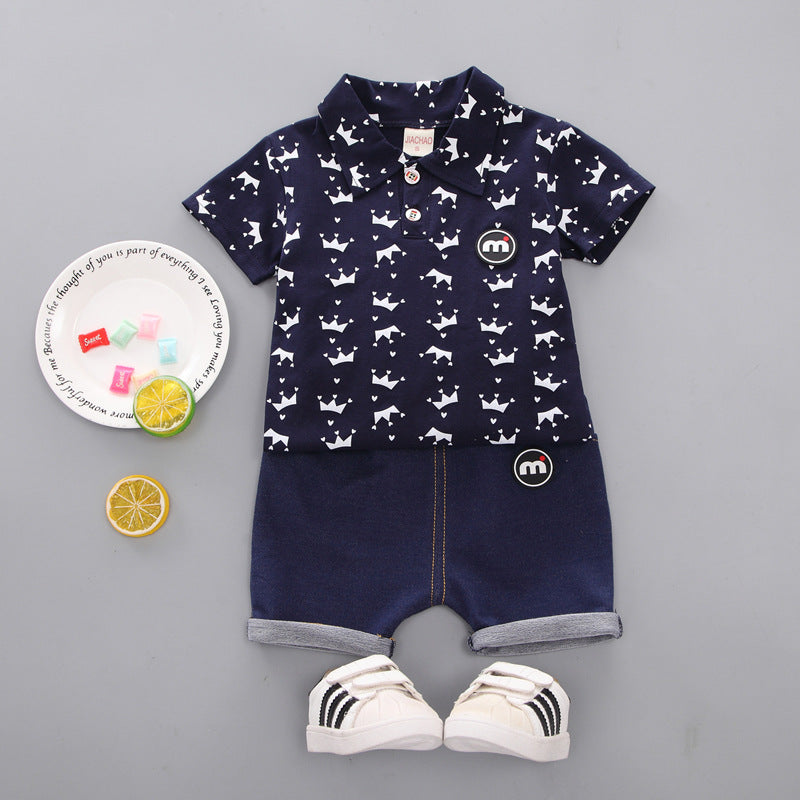 Half-sleeve suit shirt featuring a navy blue design with white crown patterns, paired with denim shorts and casual sneakers.