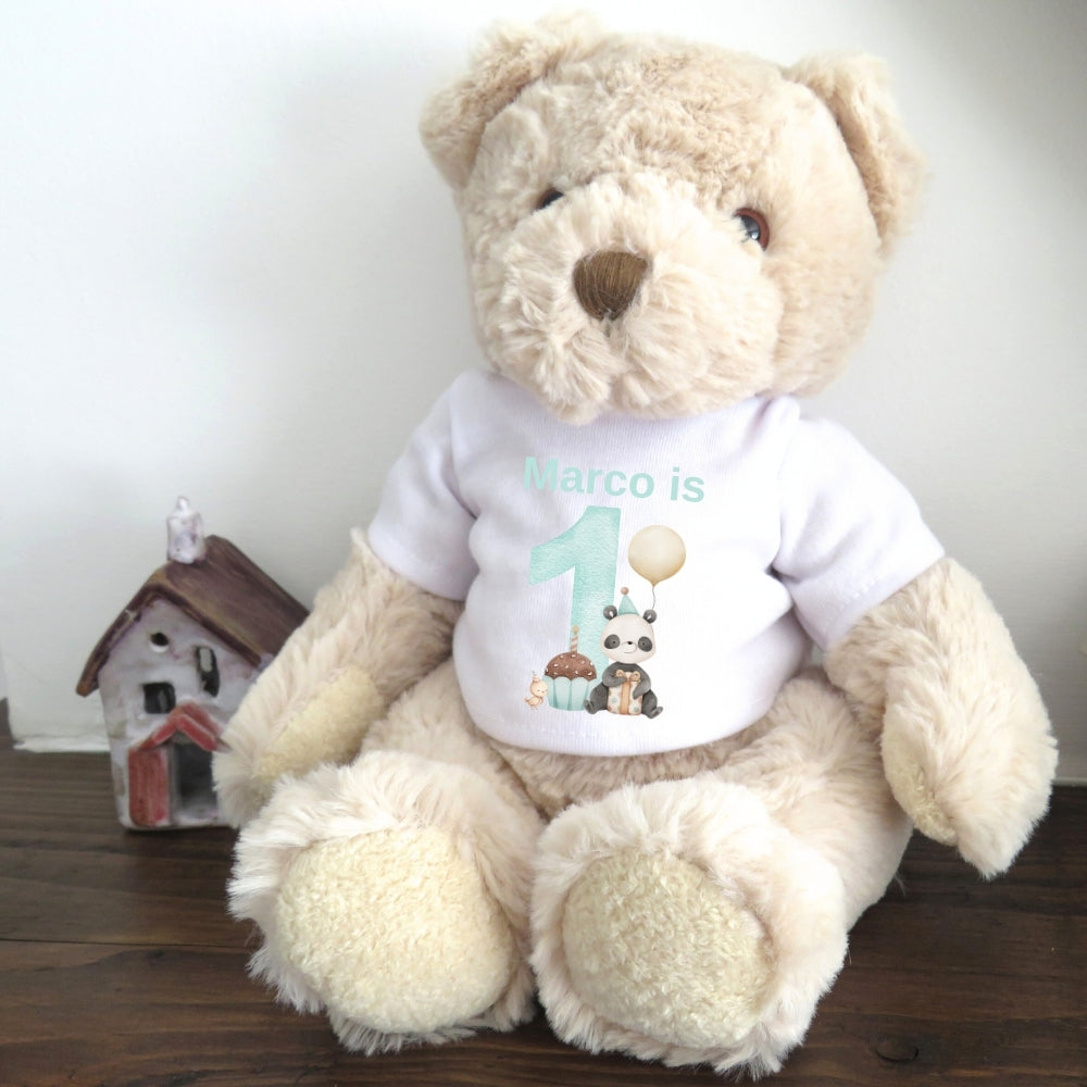 Personalised luxury teddy bear wearing a white t-shirt that says "Marco is 1!" with panda and cupcake graphics.