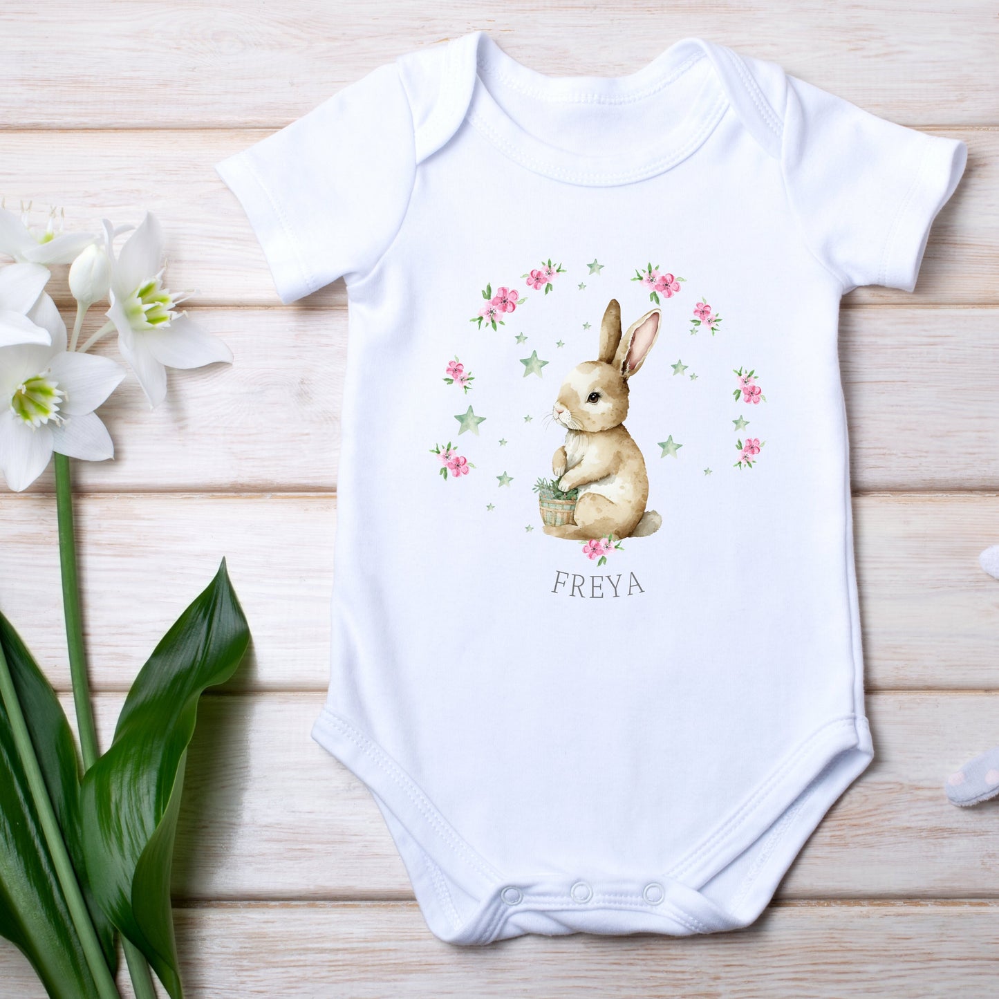 Personalised girls' bunny baby outfit featuring a white baby grow with a bunny design and the name "FREYA."