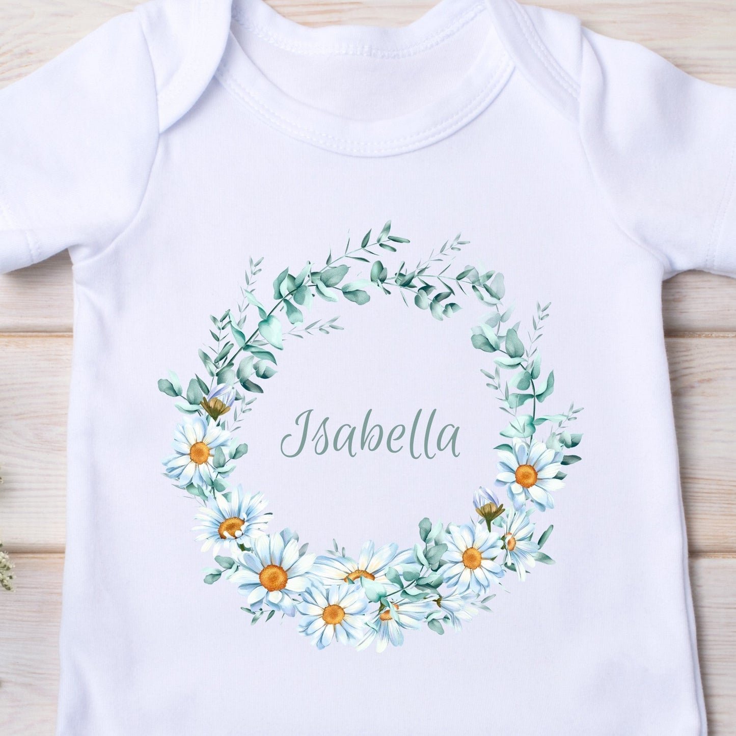Personalised Daisy Flowers Baby Outfit featuring a white vest with a floral wreath and the name "Isabella" in the center.