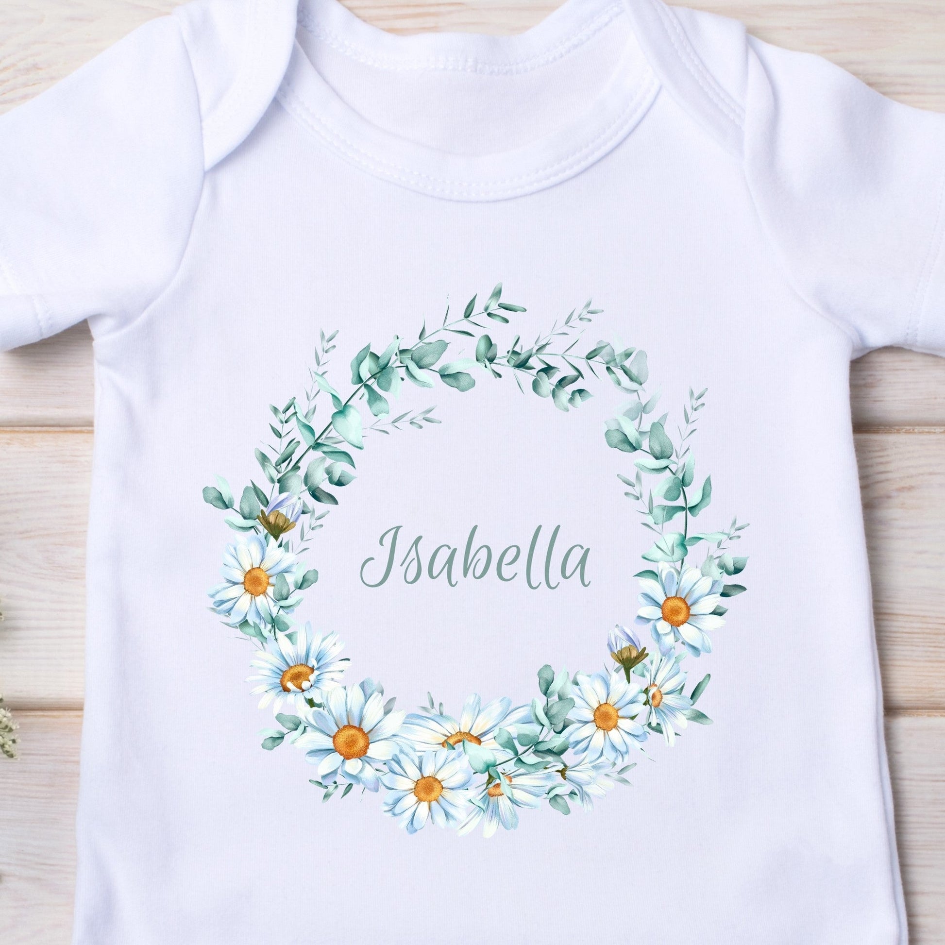 Personalised Daisy Flowers Baby Outfit featuring a white vest with a floral wreath and the name "Isabella" in the center.