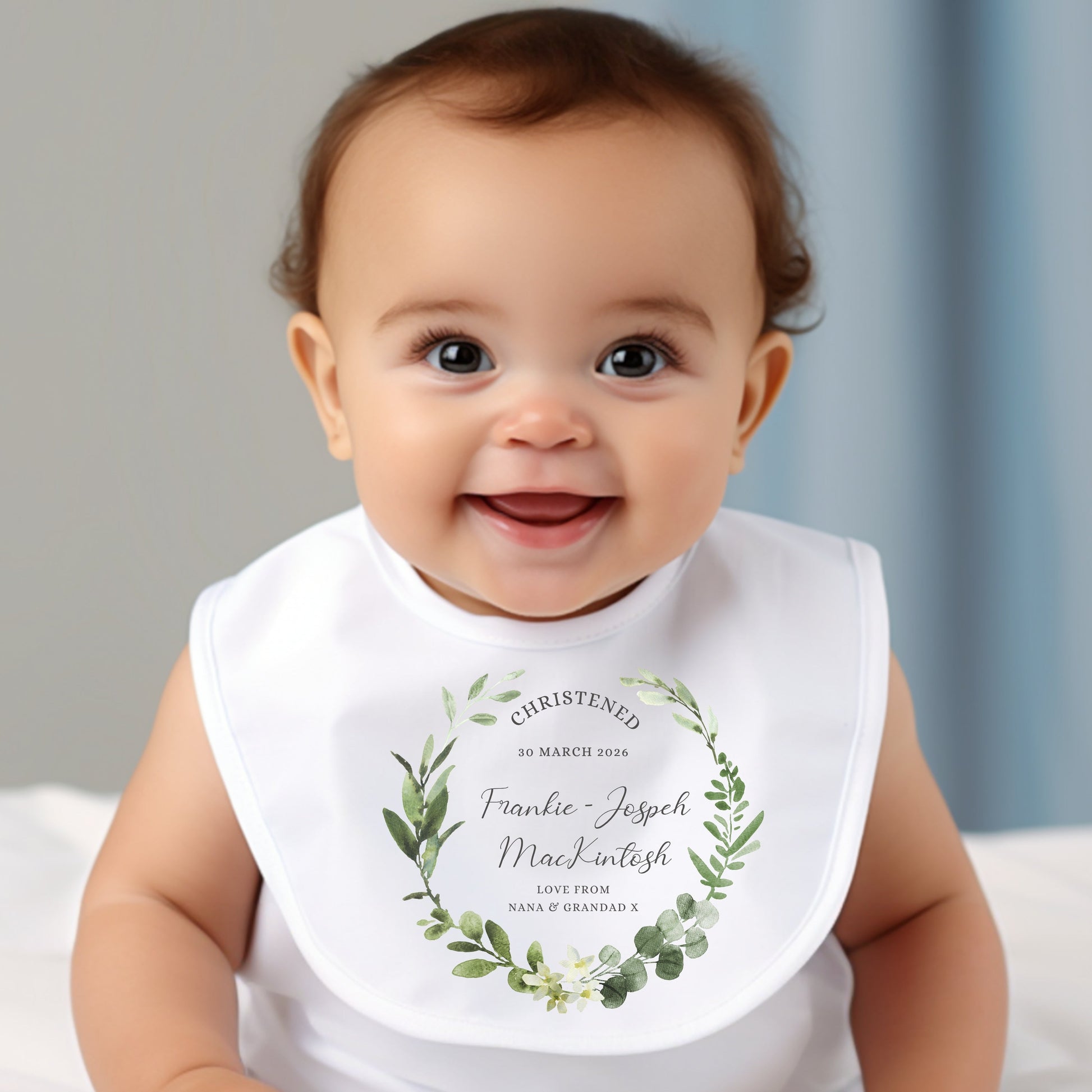 Personalised Christening Day Baby Outfit featuring a bib with floral design and text, worn by a smiling baby.