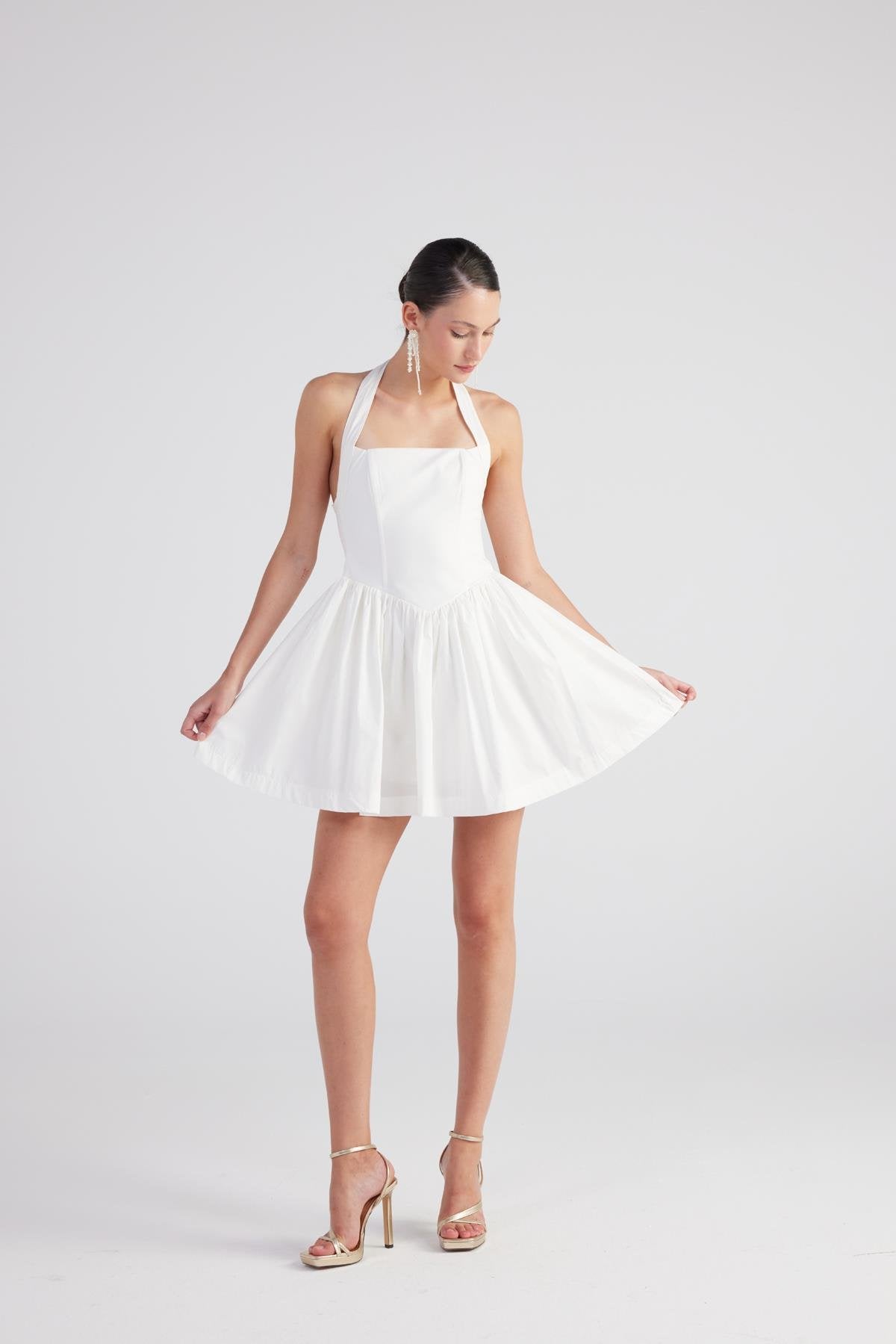 Teresa White Pleated Skirt Mini Dress featuring a halter neckline and flared skirt, styled with strappy heels.