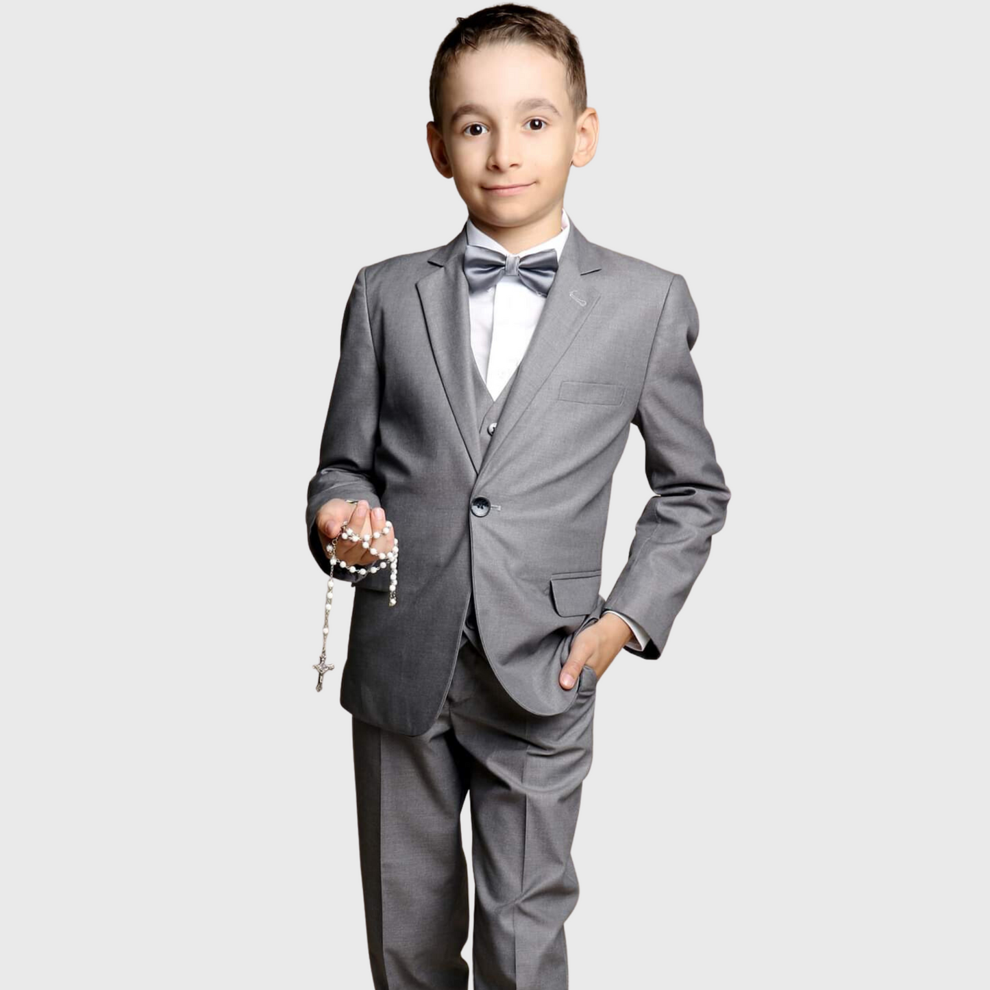 Classic Groom Boys Suits in gray, featuring a blazer, bow tie, and dress pants. The boy holds a rosary and smiles.