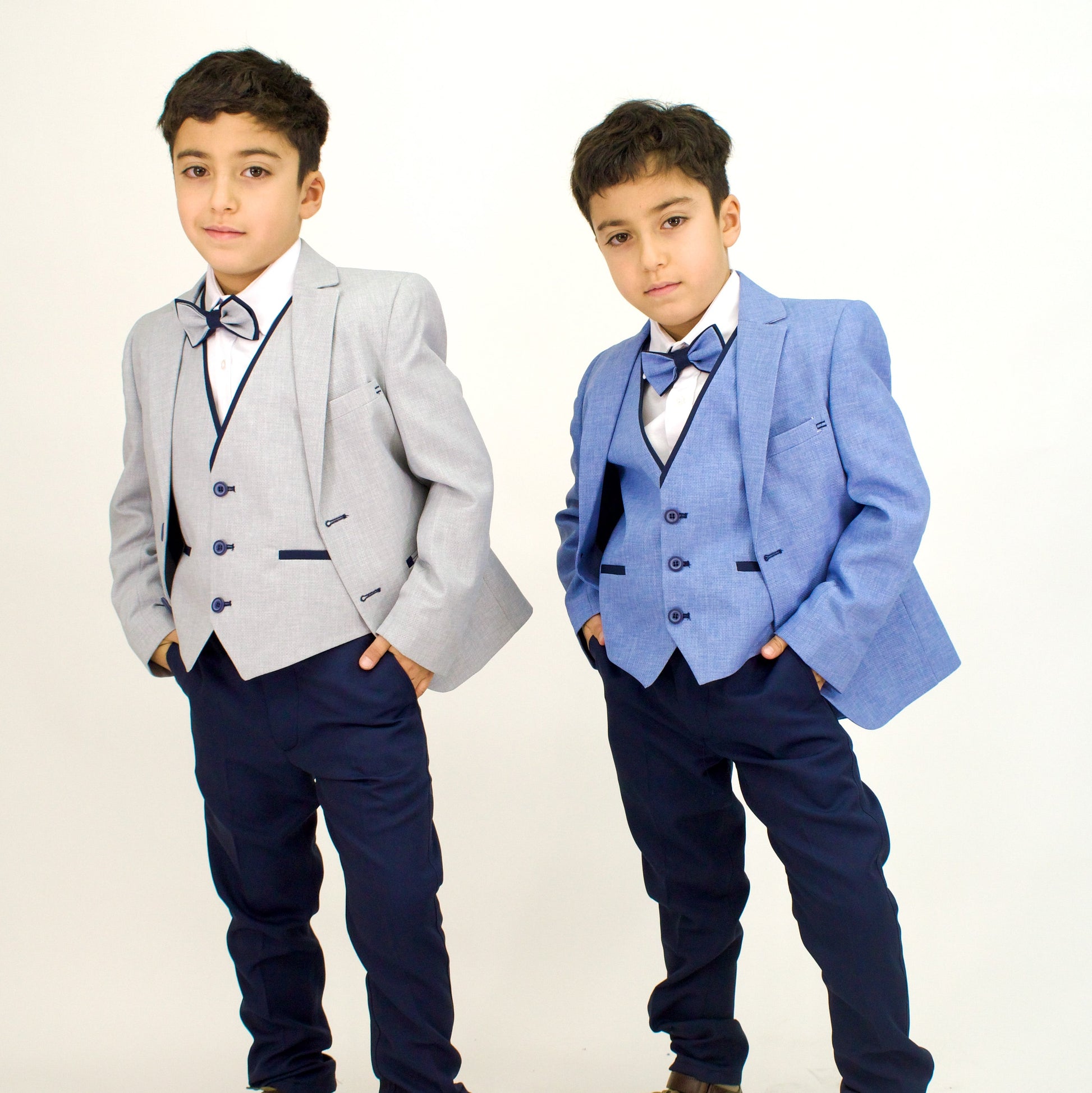 Two boys wearing Captain Stylish Formal Boys Suits in light gray and blue, each with a bow tie and dress pants.