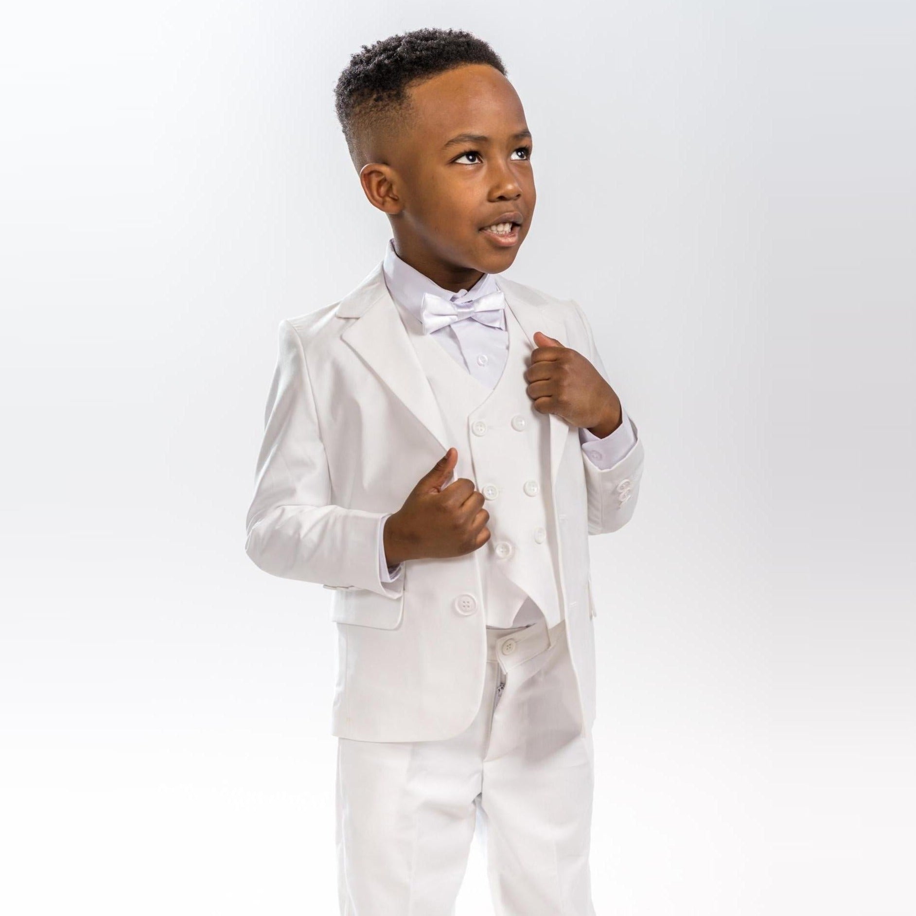 Classic Groom Boys Suits featuring a young boy in a white tuxedo with a bow tie, looking confident and stylish.