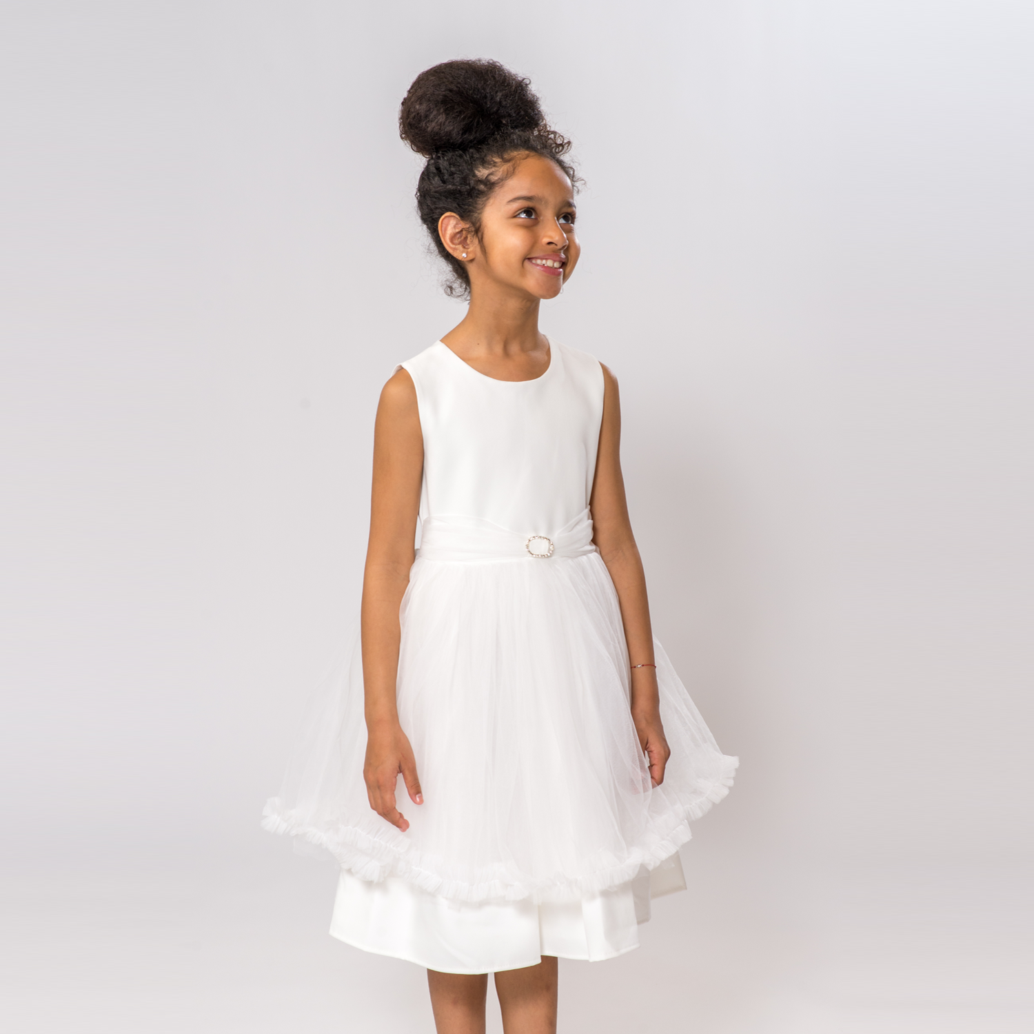 Claudia's Fancy Girl Dress features a white sleeveless design with a tulle skirt and a decorative belt.