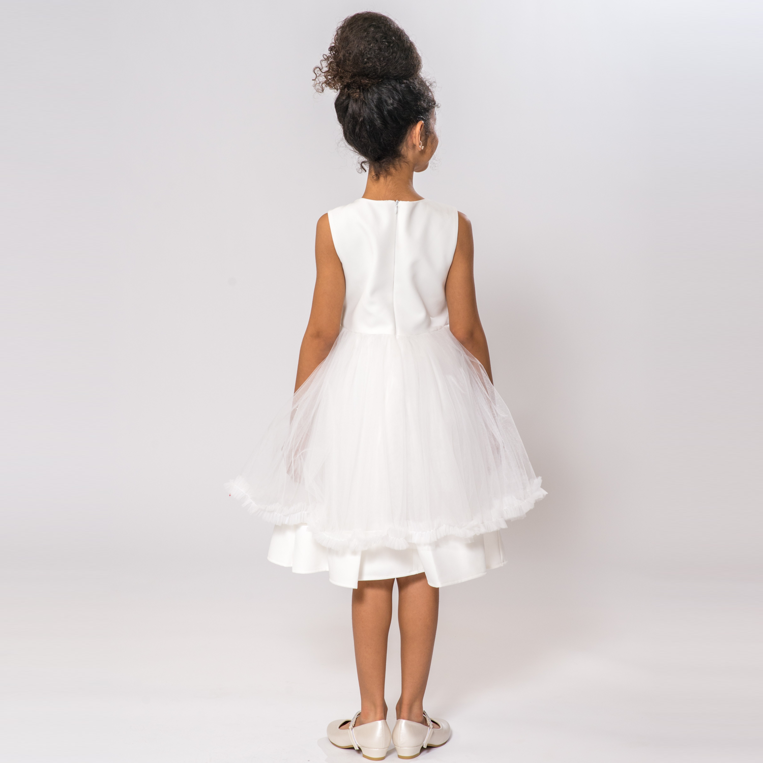 Claudia's Fancy Girl Dress features a white sleeveless design with a tulle overlay and a flared skirt, shown from the back.