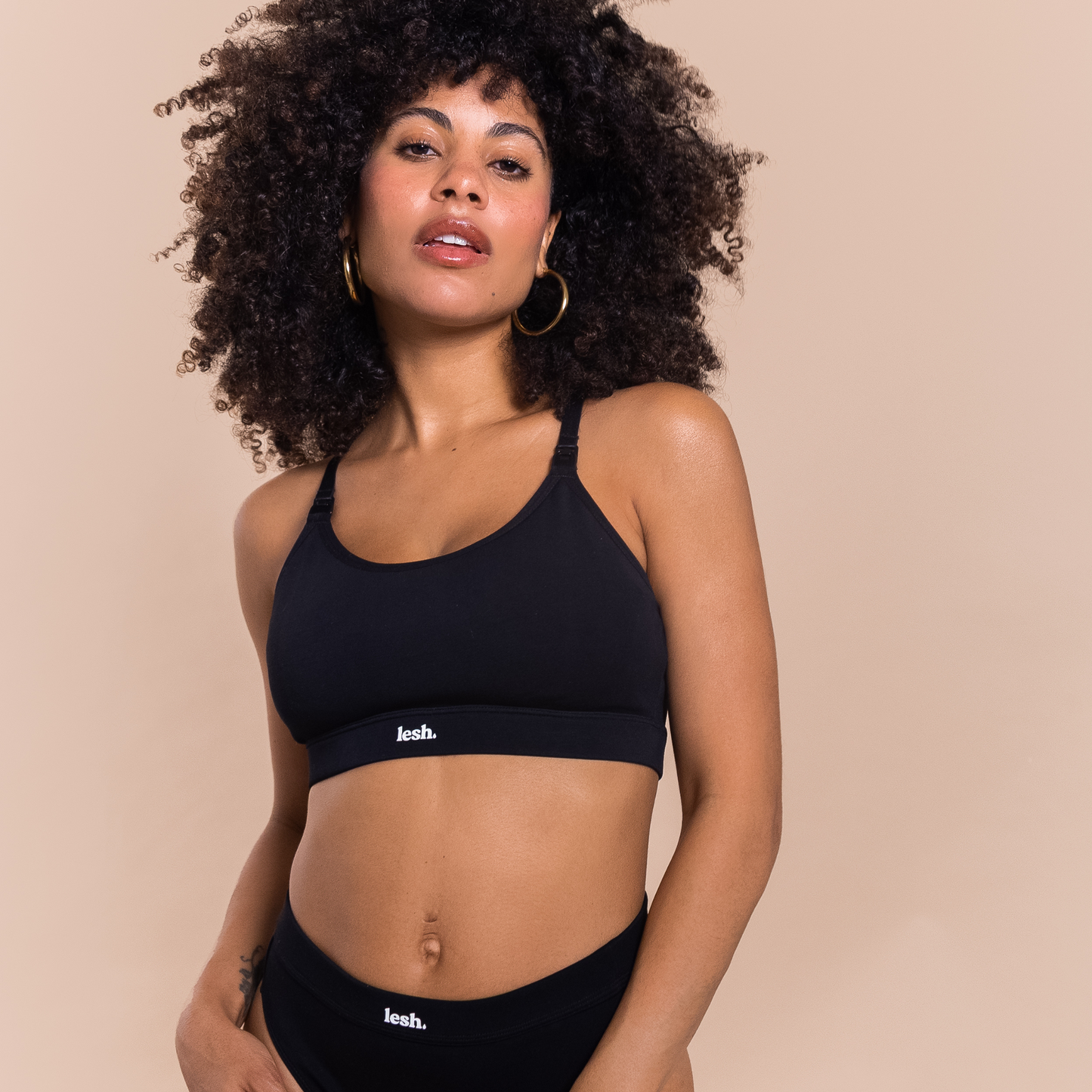 Black LESH FREEFLO 2.0 leakproof nursing bra modeled by a woman with curly hair, showcasing a comfortable design.