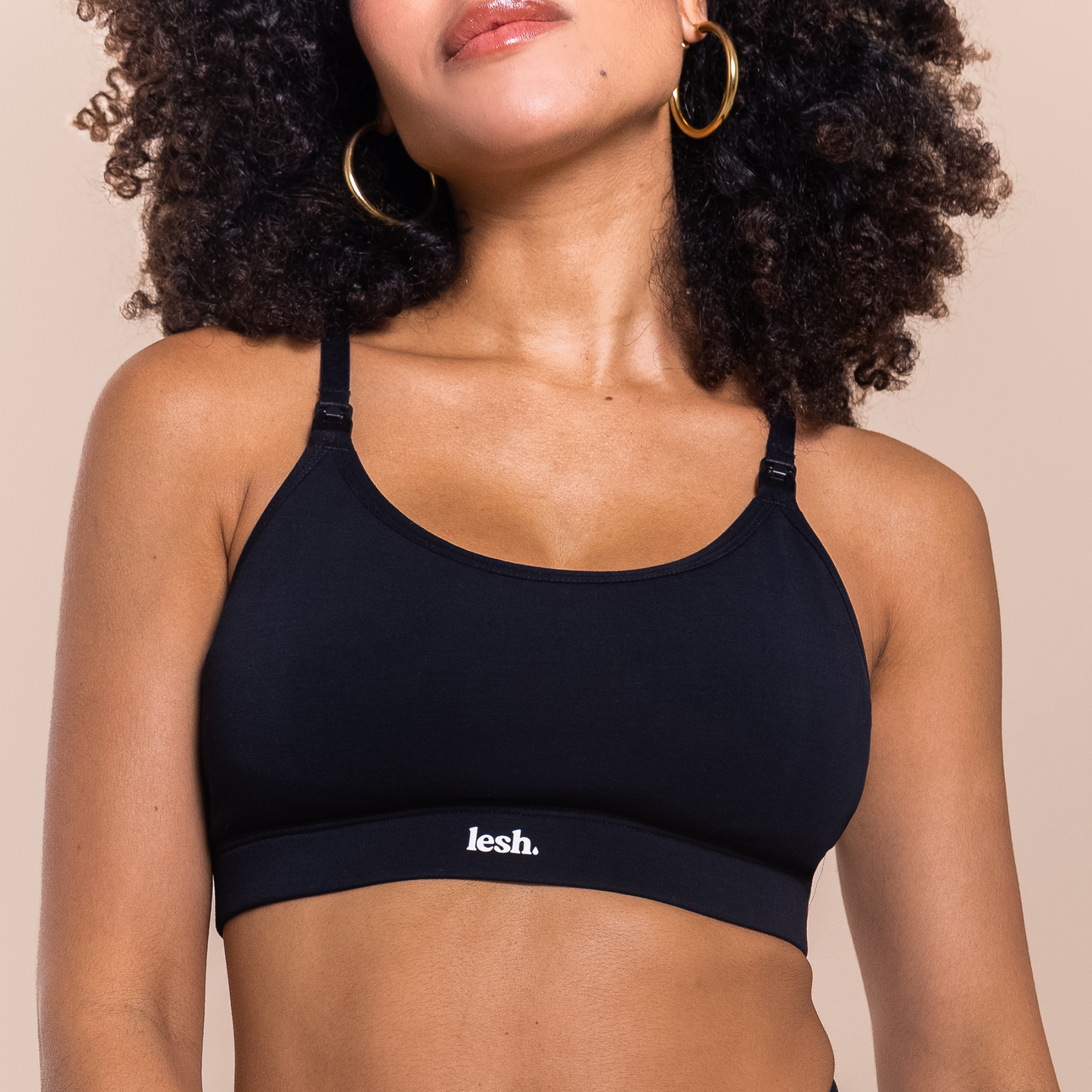 Black LESH FREEFLO 2.0 LEAKPROOF NURSING BRA on a model with curly hair, showcasing adjustable straps and logo.