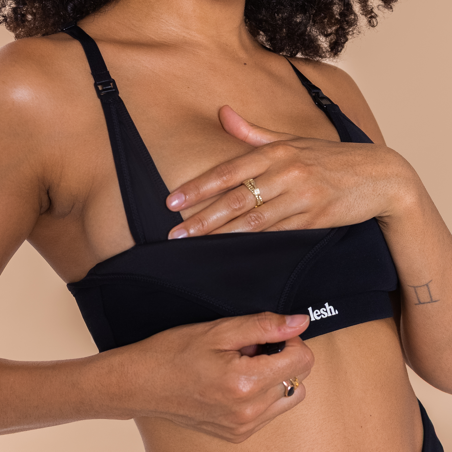 Black LESH FREEFLO 2.0 leakproof nursing bra being adjusted by a person, showcasing its easy access design.