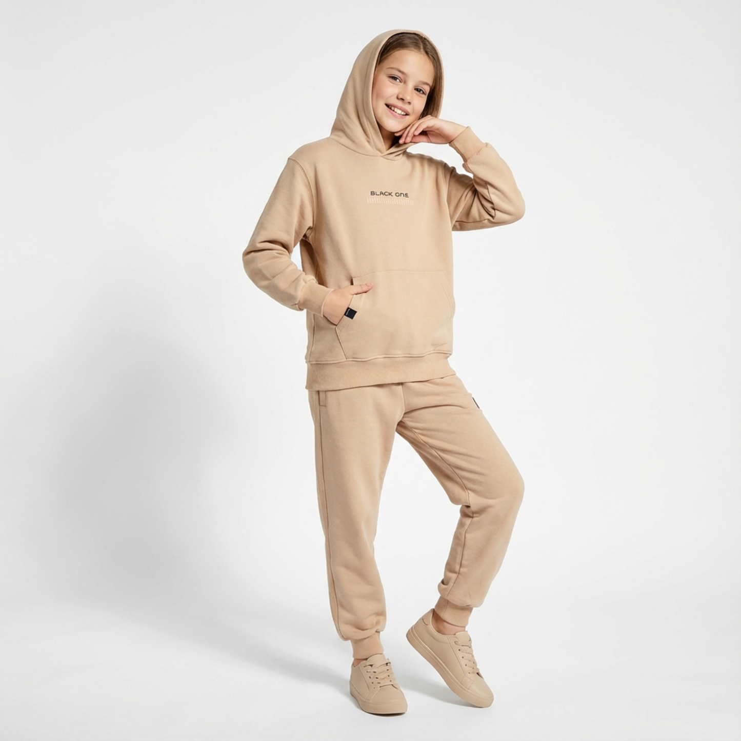 Unisex Classic Hoodie Jogger Set in beige, featuring a hood, front pocket, and matching joggers. Model poses with a smile.