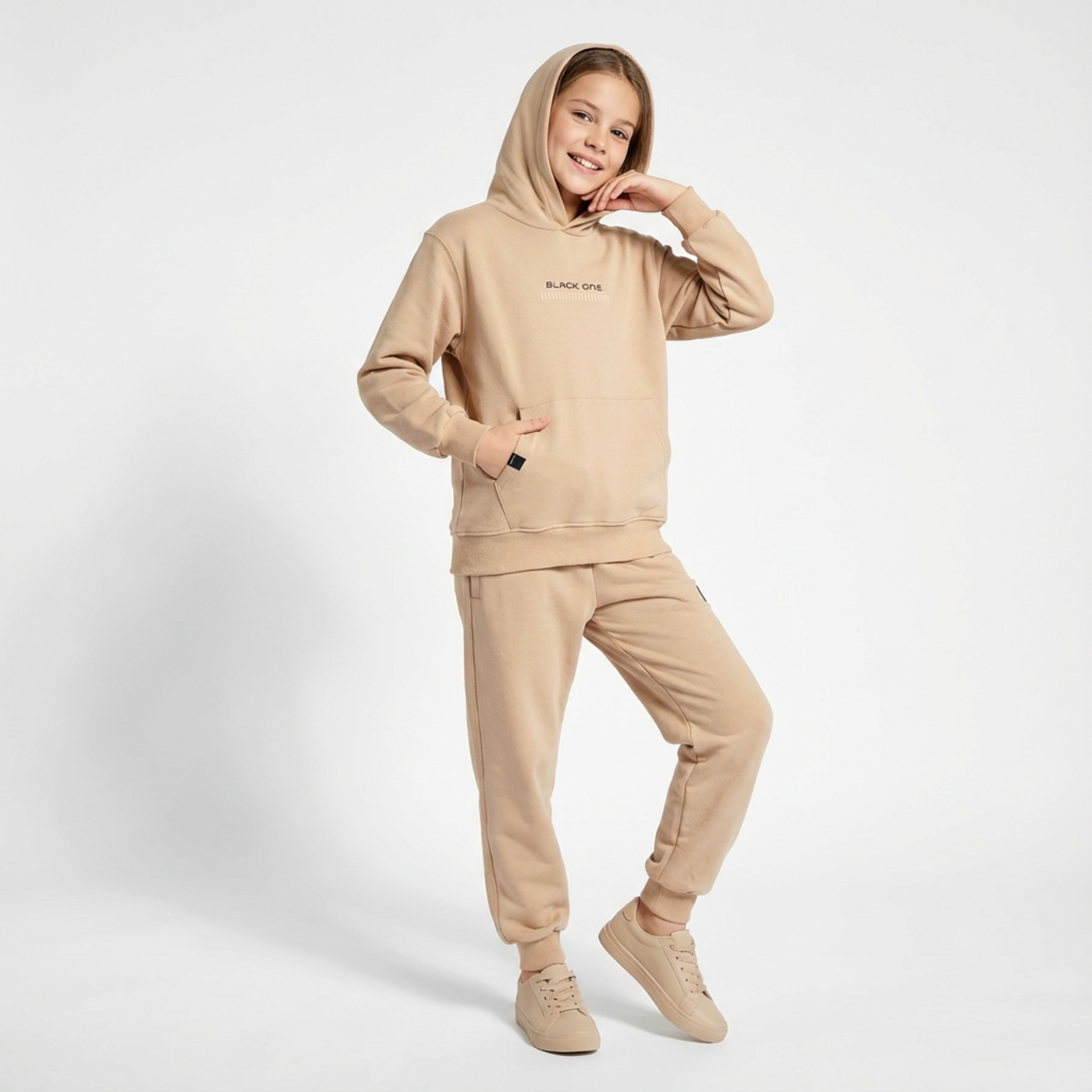 Unisex Classic Hoodie Jogger Set in beige, featuring a hood, front pocket, and matching joggers. Model poses with a smile.