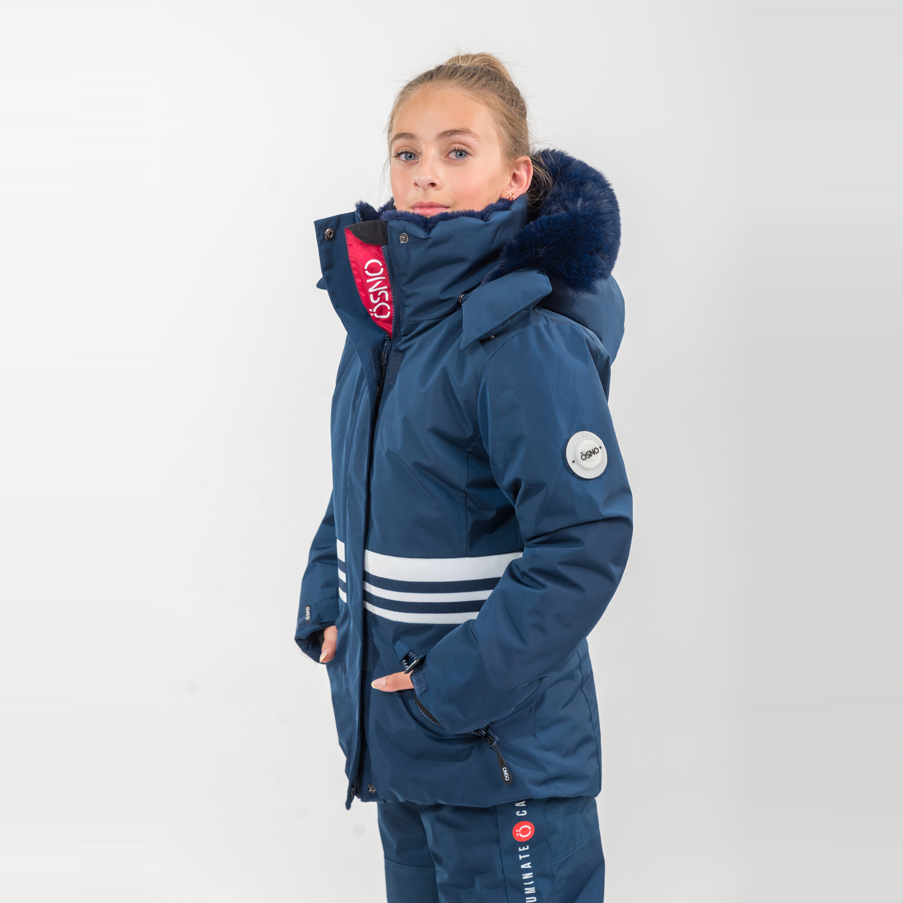 Karina's Luxury Snowsuit features a navy jacket with a fur-lined hood and matching snowpants, designed for warmth and style.