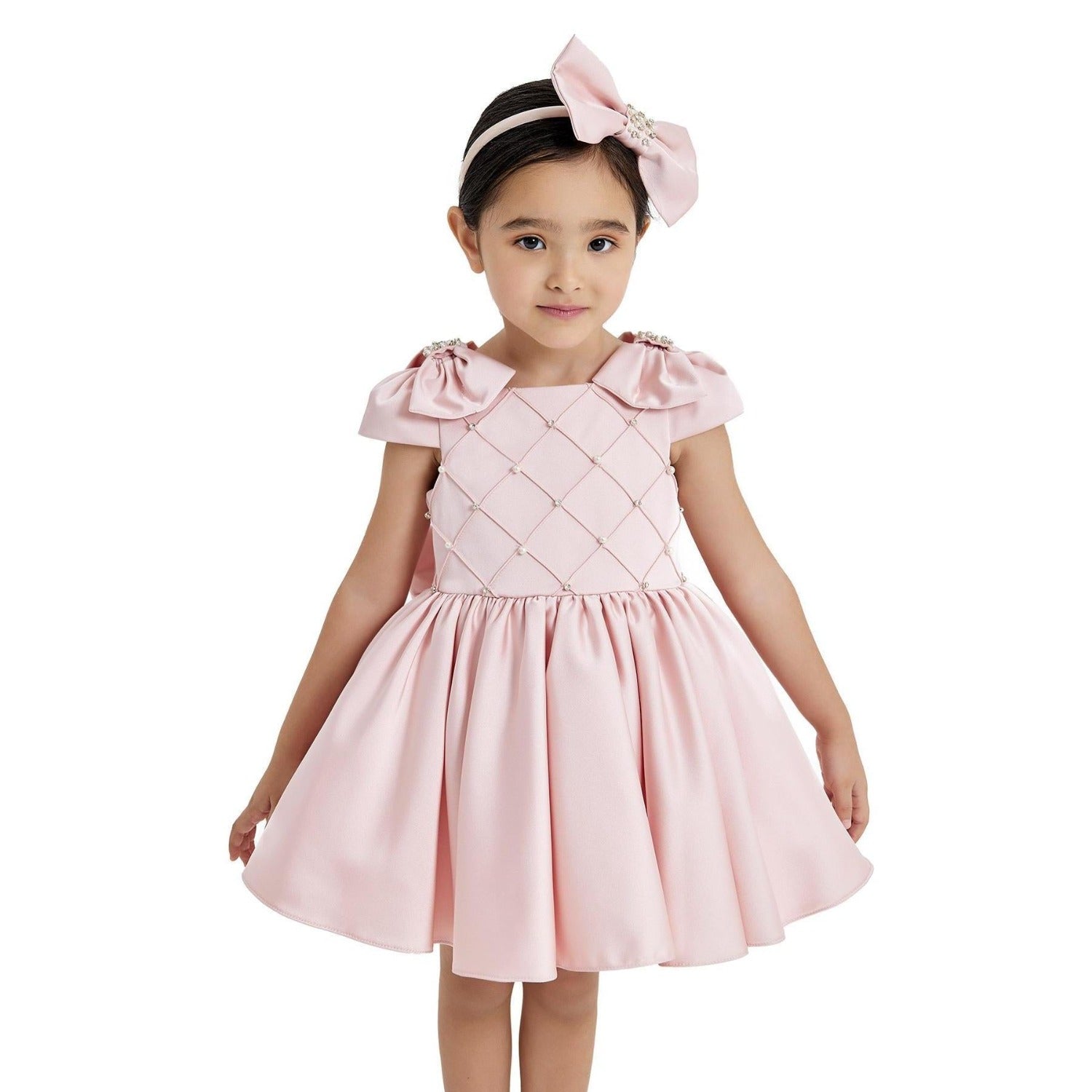 Pink formal dress for girls with bow sleeves and a quilted bodice, paired with a matching bow headband.
