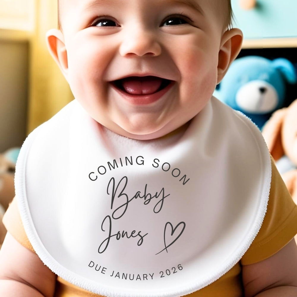 Personalised Coming Soon Baby Outfit featuring a smiling baby wearing a bib with "Coming Soon Baby Jones" text.