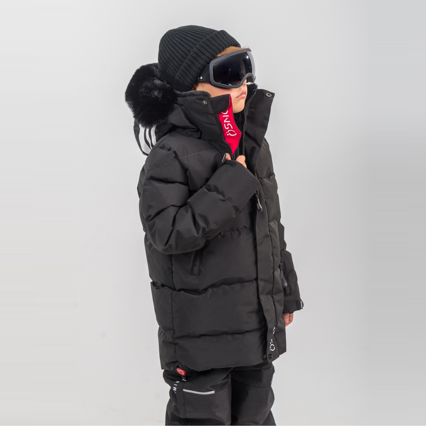 Rafa's Luxury Snowsuit features a black puffy jacket and snowpants, paired with a beanie and oversized goggles.