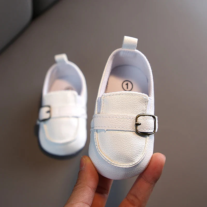 White first steps shoes for children with a buckle detail, designed for comfort and style. Ideal for early walkers.