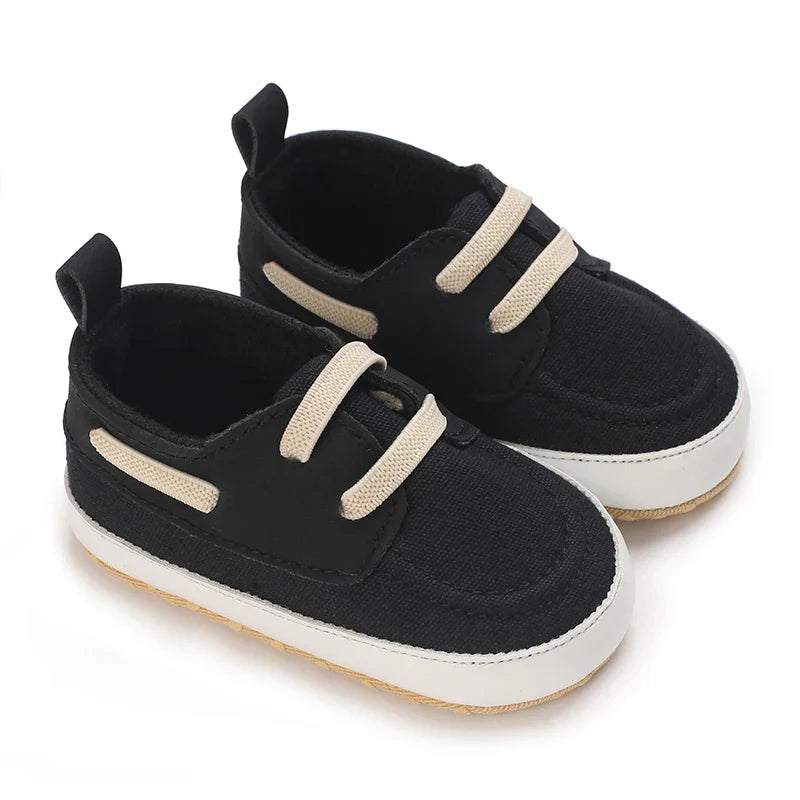 Black First Steps Shoes for Children with beige laces and a white rubber sole, designed for comfort and style.