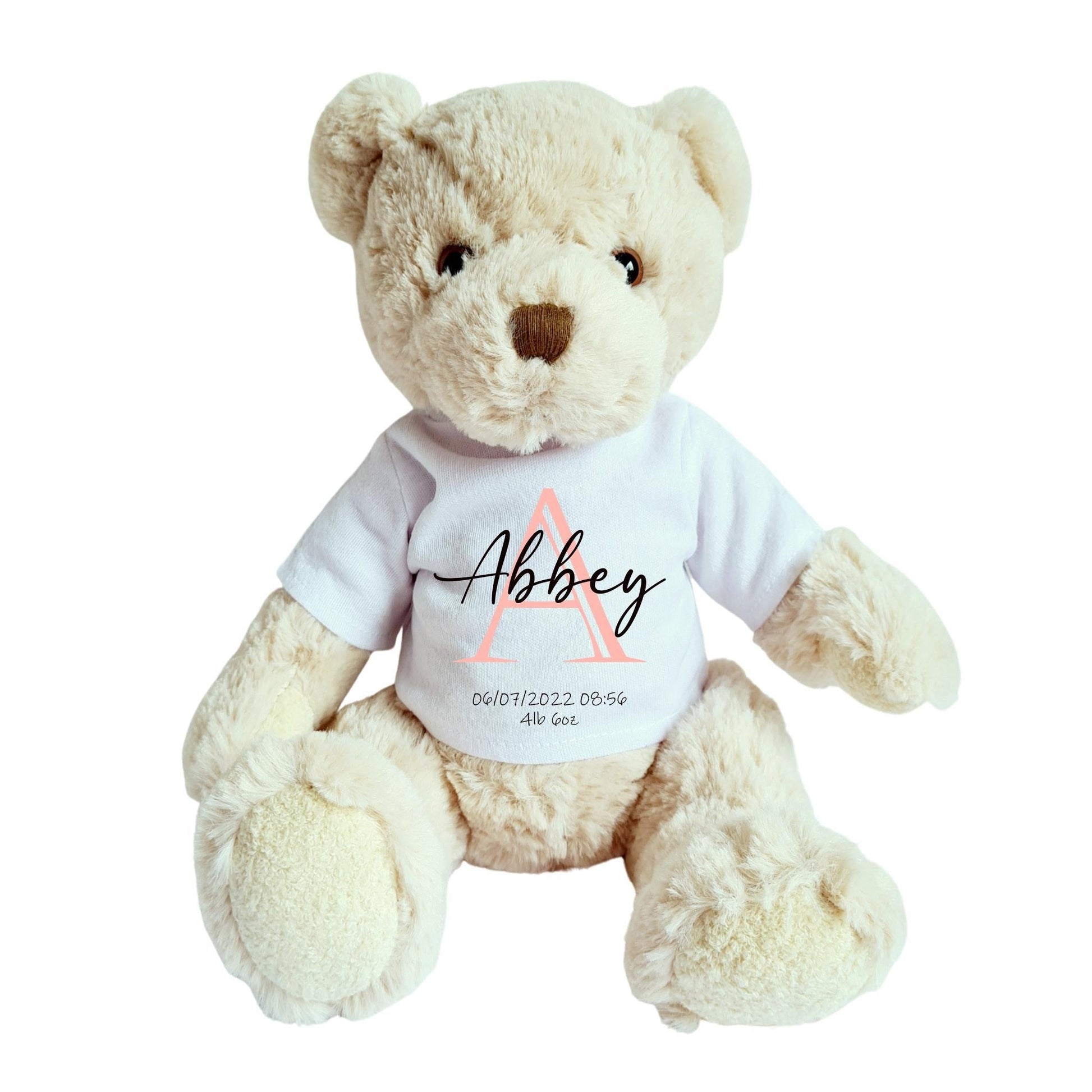 Teddy bear wearing a personalized white shirt with a pink initial "A" and the name "Abbey" printed on it.
