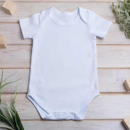 Personalised Pink Initial Bunny Baby Outfit featuring a white short-sleeve vest, surrounded by greenery and wooden blocks.
