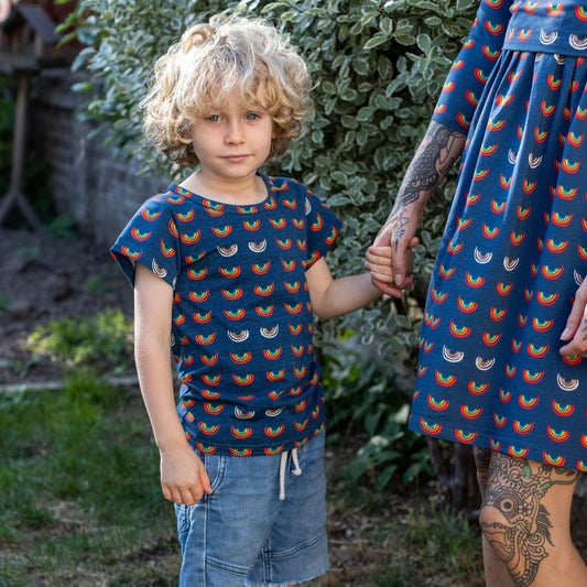Boob Over the Rainbow Kids top featuring a colorful rainbow pattern, worn by a child holding hands with an adult.
