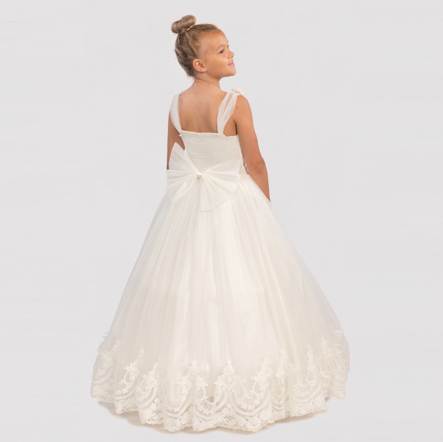 Bianca Princess Girls Formal Dress features a white tulle design with a large bow at the back and intricate lace detailing.