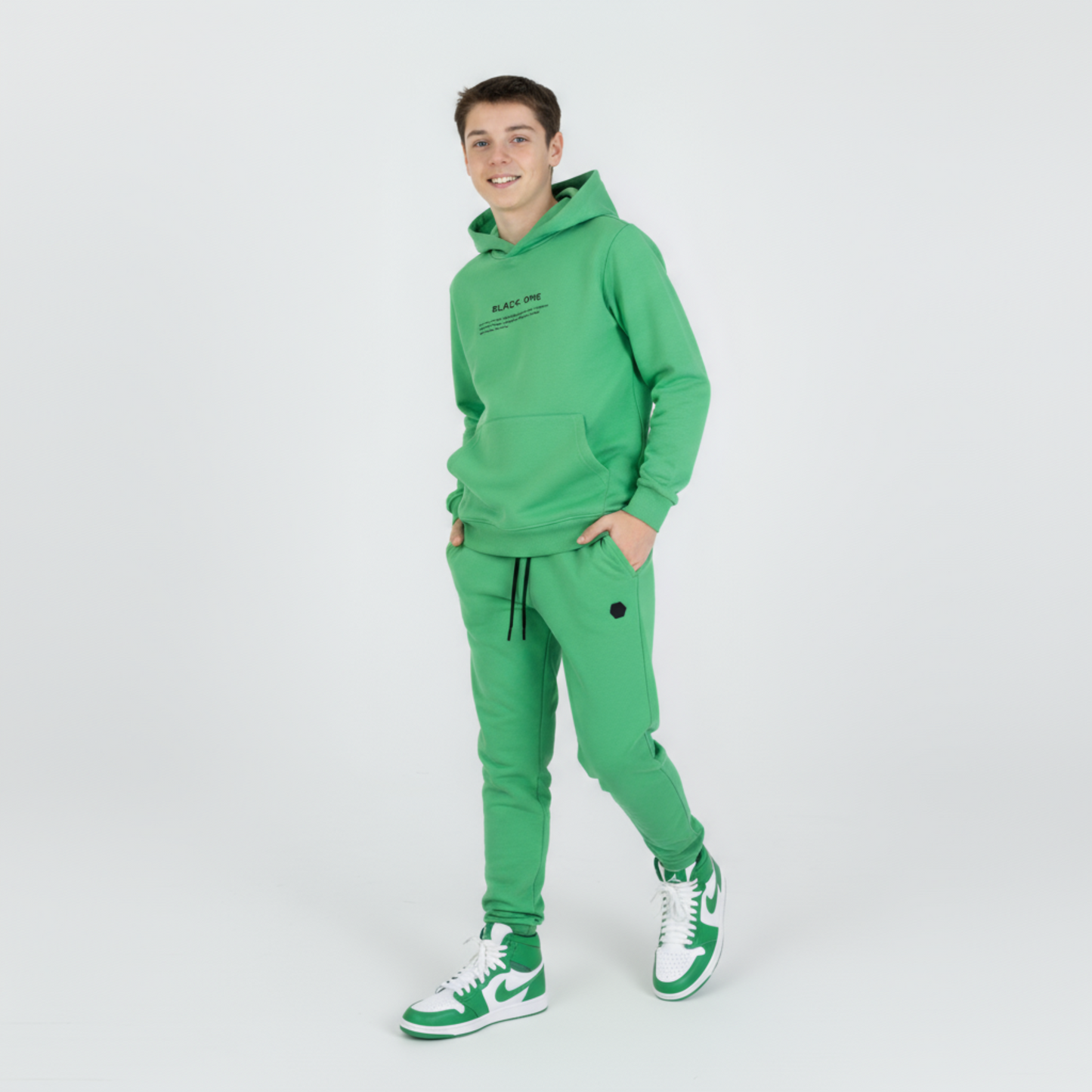 Unisex Classic Hoodie Jogger Set in green, model wearing hoodie with pocket and matching joggers, paired with white and green