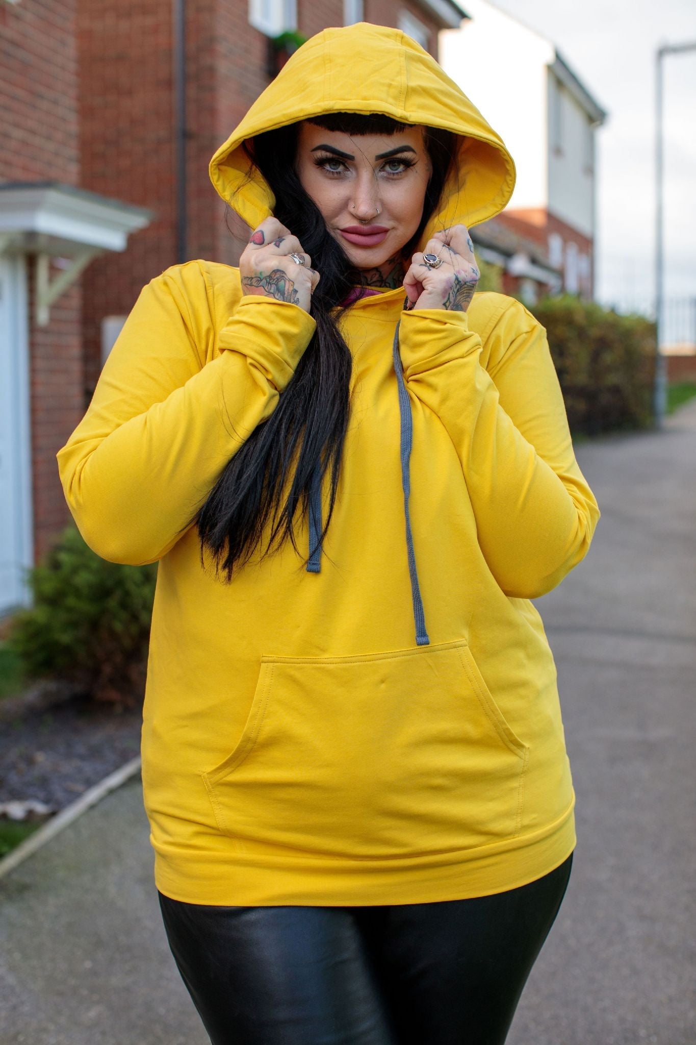 Yellow breastfeeding hoodie featuring a front pocket and adjustable drawstring hood, modeled by a woman outdoors.