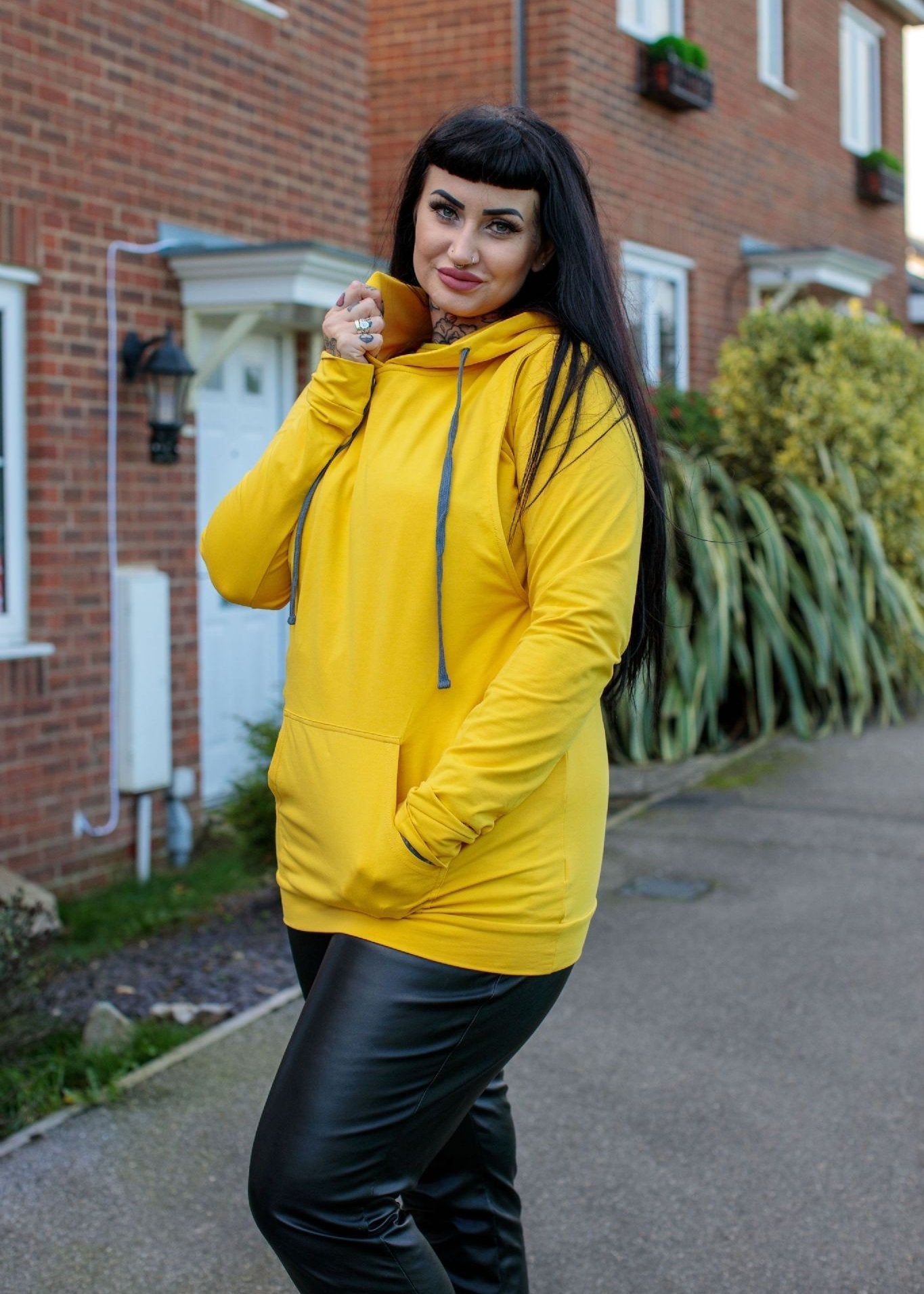 Yellow breastfeeding hoodie featuring a front pocket and adjustable drawstring hood, modeled outdoors.