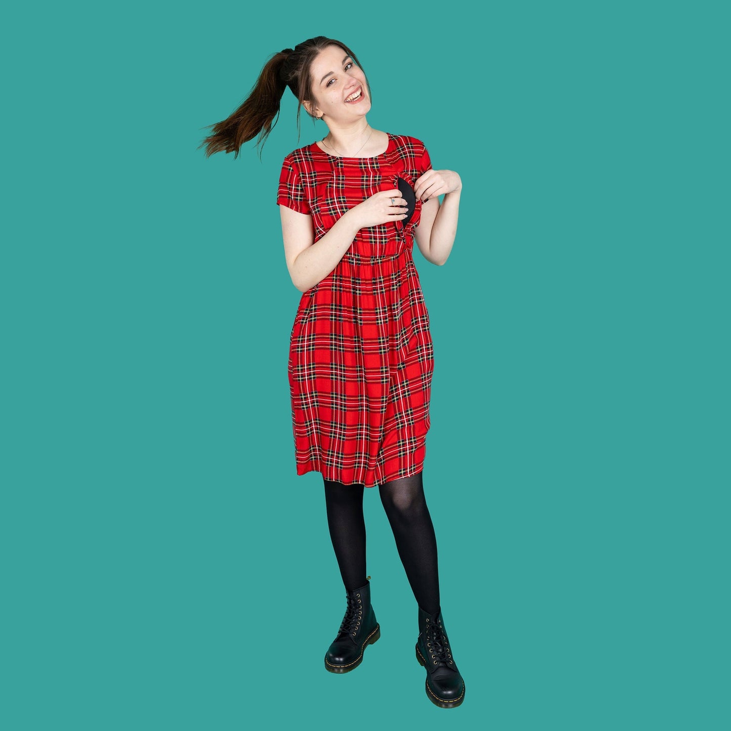 Knee length red tartan cotton breastfeeding dress, featuring short sleeves and a relaxed fit, paired with black boots.