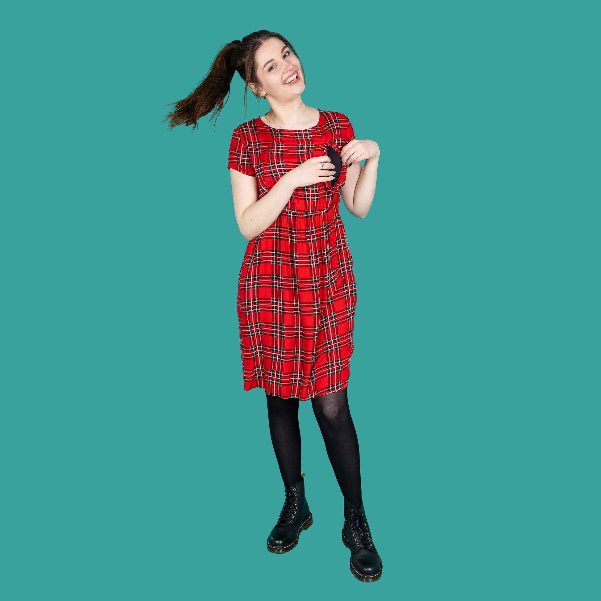 Knee length red tartan cotton breastfeeding dress, featuring short sleeves and a relaxed fit, paired with black boots.
