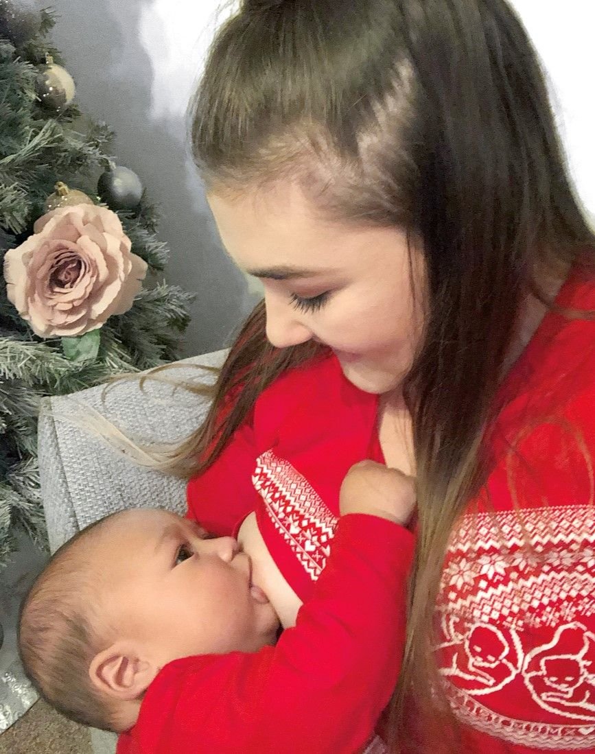 Red Heart Breastfeeding Top featuring a mother nursing her baby, both in cozy red outfits, with a festive background.
