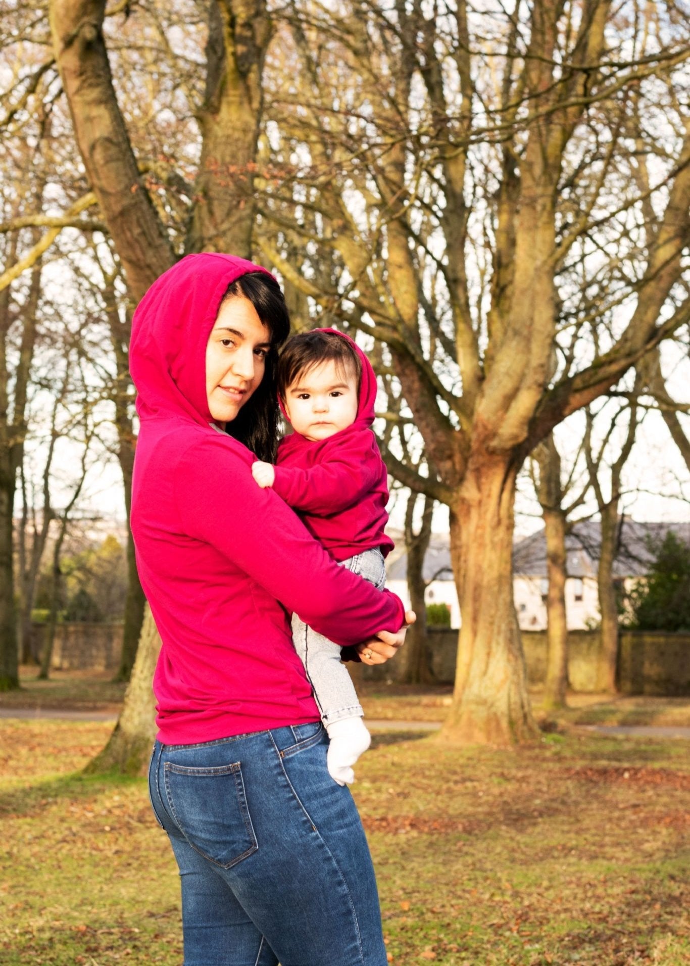 MilkyMoon Kid Hoodie in vibrant pink, worn by a woman holding a child, both smiling outdoors among trees.