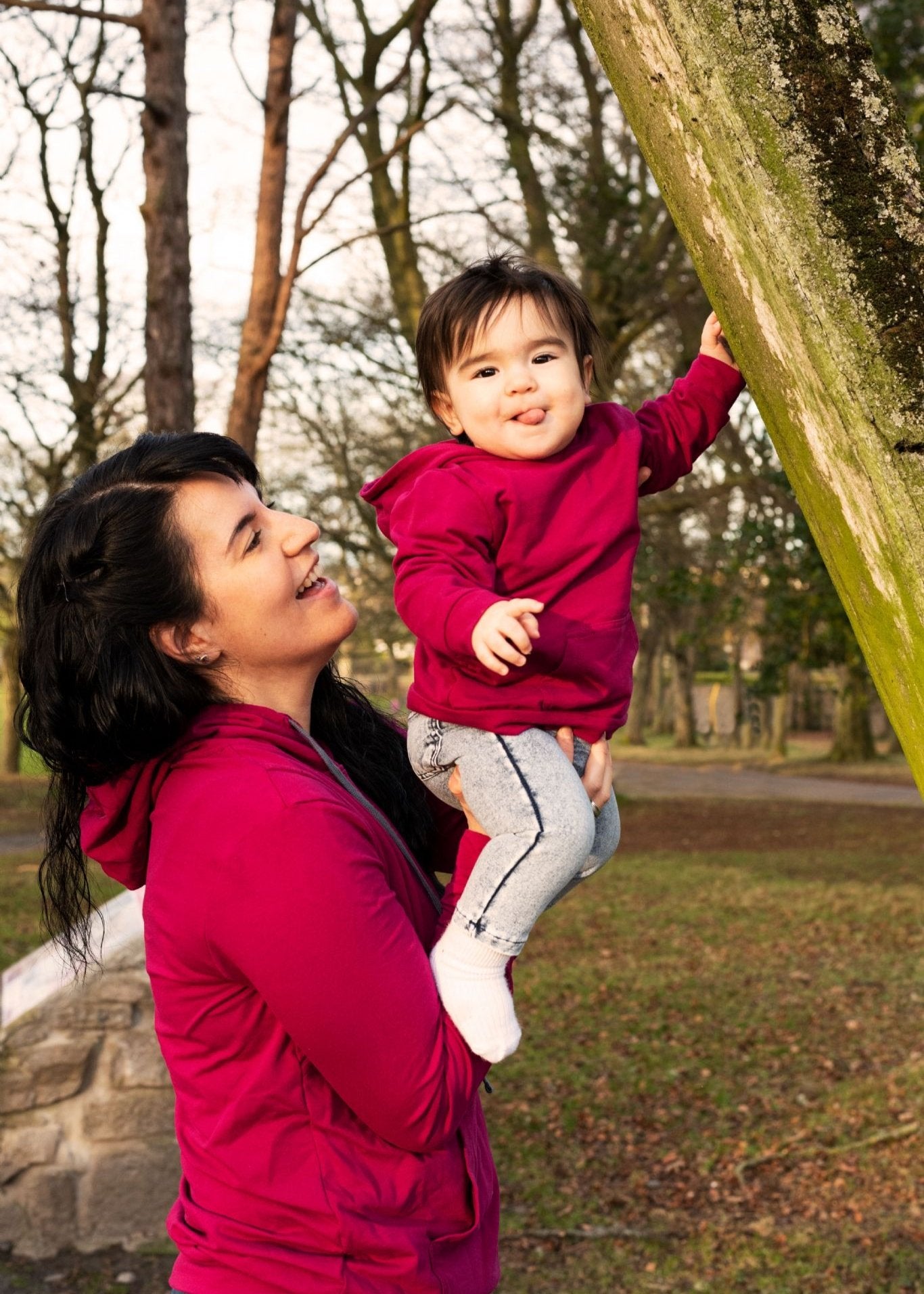 MilkyMoon Kid Hoodie in vibrant pink, worn by a child being held by an adult in a park setting.