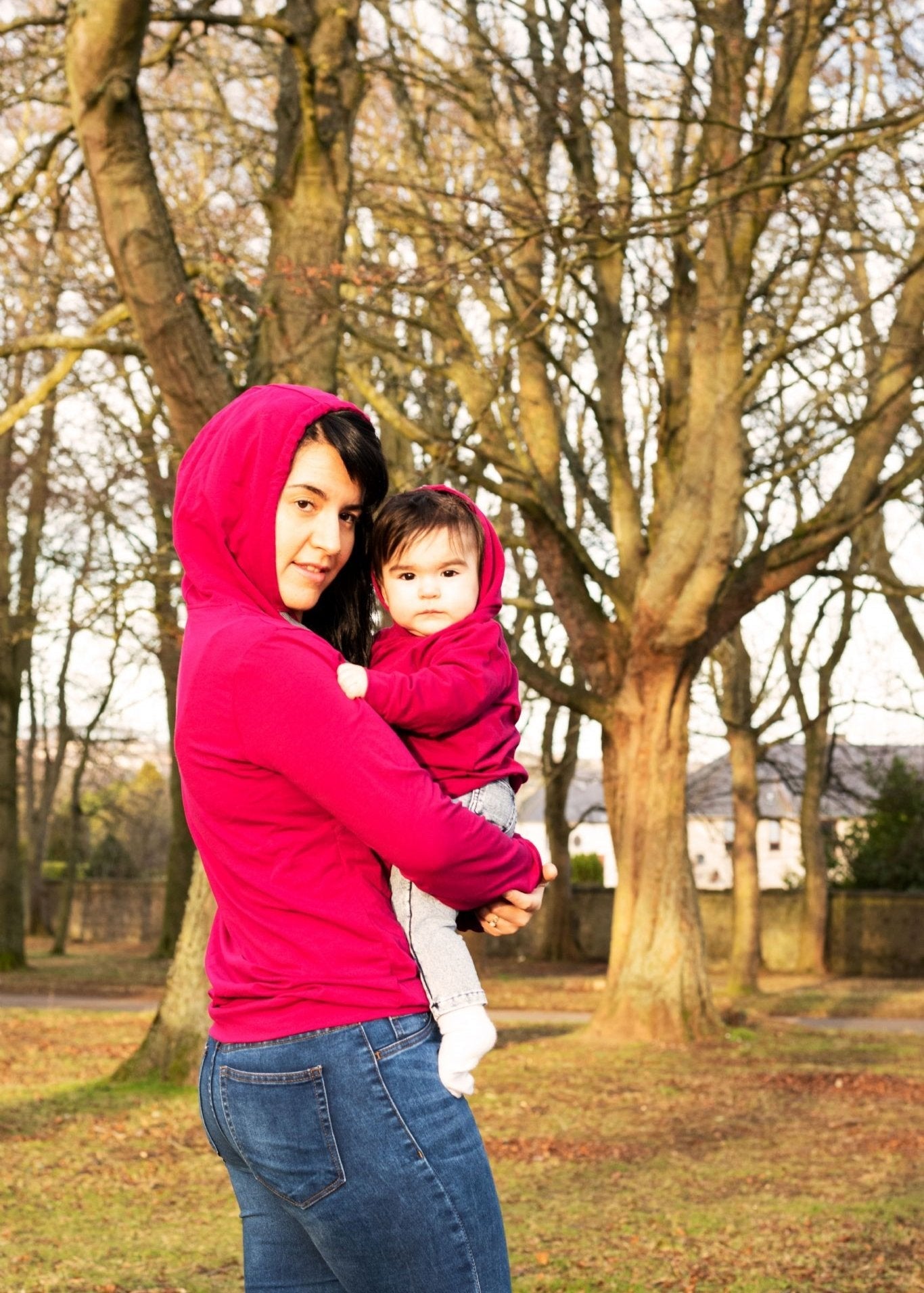 MilkyMoon Kid Hoodie worn by a mother holding her child, both in matching red hoodies, outdoors among trees.